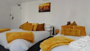 A hotel room with two beds, each with white linens and multiple pillows. There is a painting on the wall above the beds. - Kings Arms Hotel (Holsworthy)