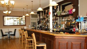 A bar area with wooden chairs, a bar counter, and hanging lights. - Kings Arms Hotel (Holsworthy)