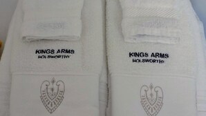 Two white towels with embroidered text and a heart design, labeled 'Kings Arms Holsworthy'. - Kings Arms Hotel (Holsworthy)