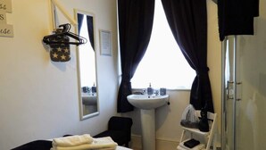 A hotel room with a bed, a bathroom with a sink and mirror, and a wardrobe. - Kings Arms Hotel (Holsworthy)