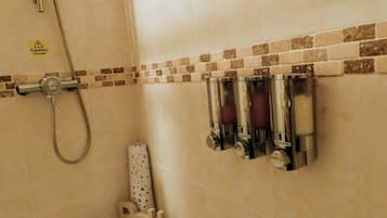 A bathroom with a shower, a bathtub, and a towel rack with soap dispensers.