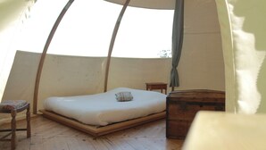 A tent with a single bed, a small wooden table, and a storage chest. - Ô bois dormant (Lempzours)