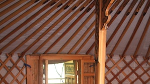 A traditional wooden yurt interior with a wooden door leading outside, a wooden chair, and a small wooden chest. - Ô bois dormant (Lempzours)