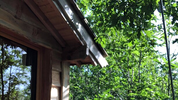 A wooden porch with a railing, a window, and a cup on the floor. - Ô bois dormant (Lempzours)