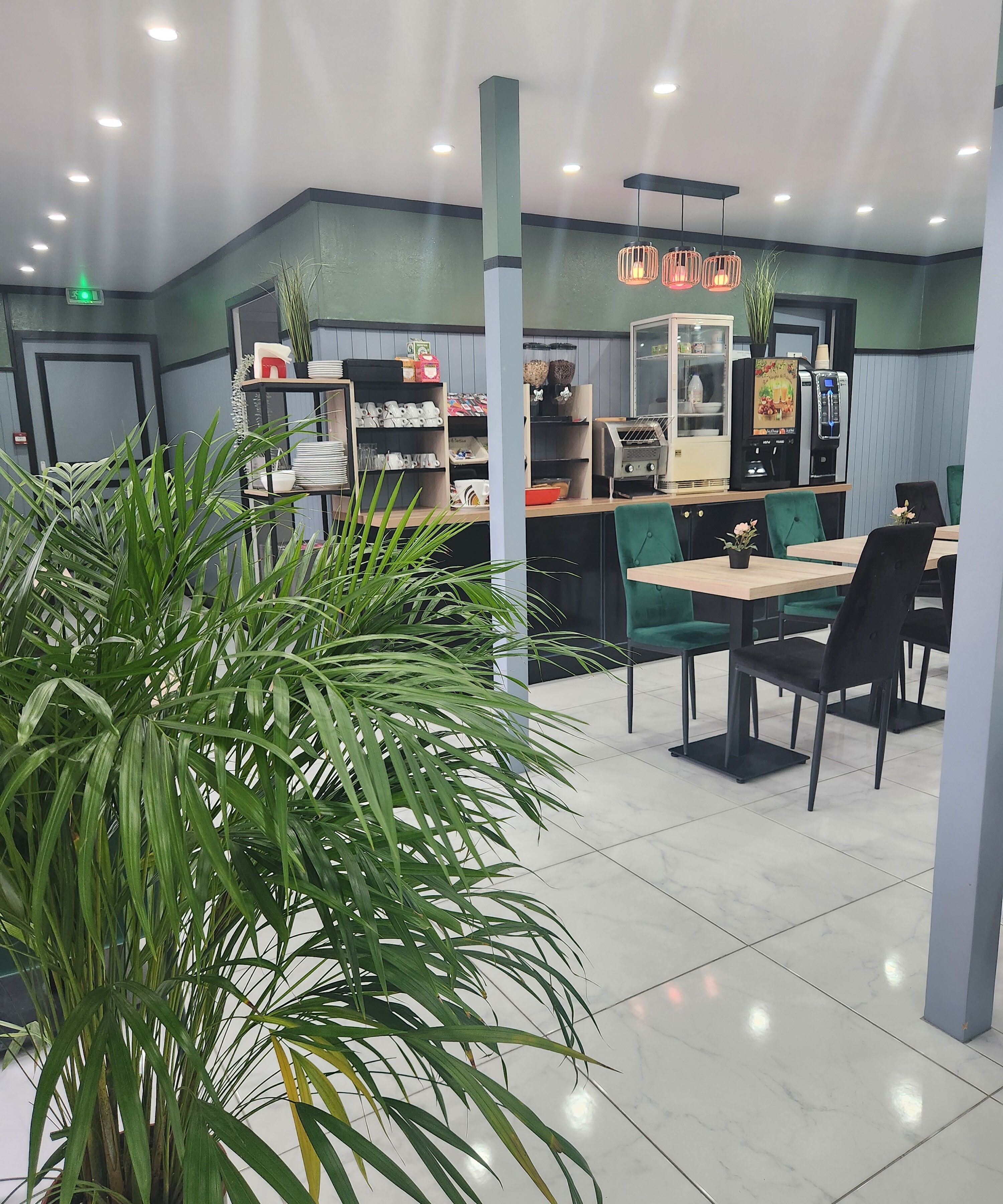 Un interior de restaurante moderno con paredes verdes, suelo de mármol y diversas opciones de asiento, como mesas y sillas.