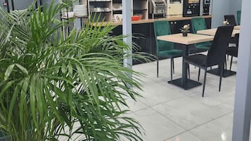 Un interior de restaurante moderno con paredes verdes, suelo de mármol y diversas opciones de asiento, como mesas y sillas.