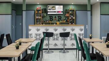 A bar area with a counter displaying various beverages, two bar stools, and a television screen above the counter.