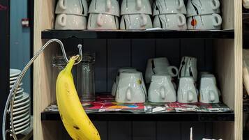 Una cocina con fruteros que contienen plátanos, manzanas y naranjas, una tetera y una caja de té Lipton.