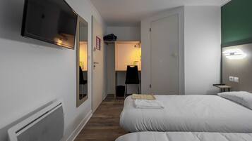 Una habitación de hotel con cama, escritorio, silla, espejo y televisor.
