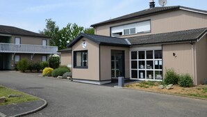 A two-story building with a beige exterior and a dark roof. There is a satellite dish on the roof and a sign with the number 24 on the front. - FASTHOTEL Le Mans Nord Saint-Saturnin - UN FH CONFORT (Saint-Saturnin)