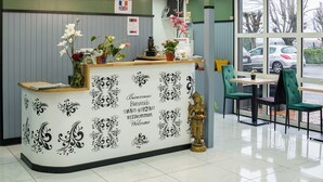 A reception area with a decorative counter, a statue, and a view of the outside. - FASTHOTEL Le Mans Nord Saint-Saturnin - UN FH CONFORT (Saint-Saturnin)