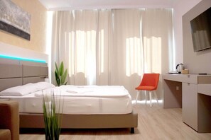 Une chambre d’hôtel moderne équipée d’un lit, d’un bureau, d’une chaise et d’une télévision.