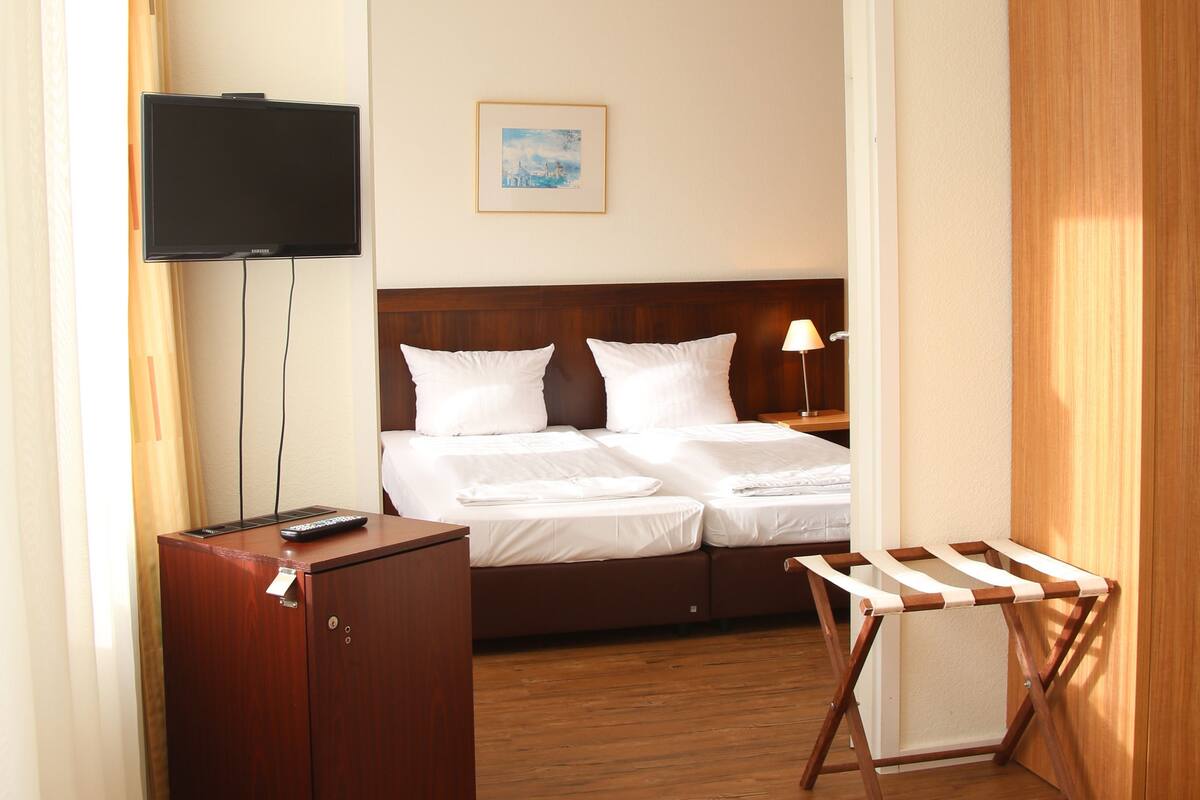A hotel room with a bed, a TV, a desk, and a wardrobe.