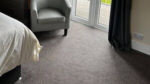 A hotel room with a bed, a chair, a wardrobe, and a sliding glass door to a balcony. - Chevin End Guest House (Ilkley)