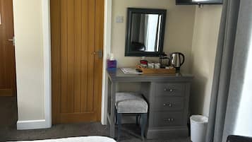 Una habitación de hotel con una cama, un escritorio con una silla, un televisor y una puerta.