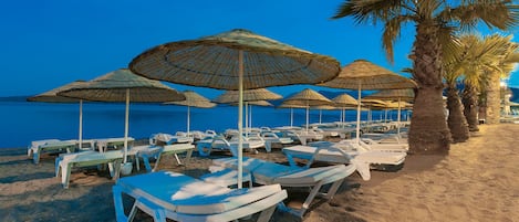 Een privéstrand, ligstoelen aan het strand, parasols, strandlakens