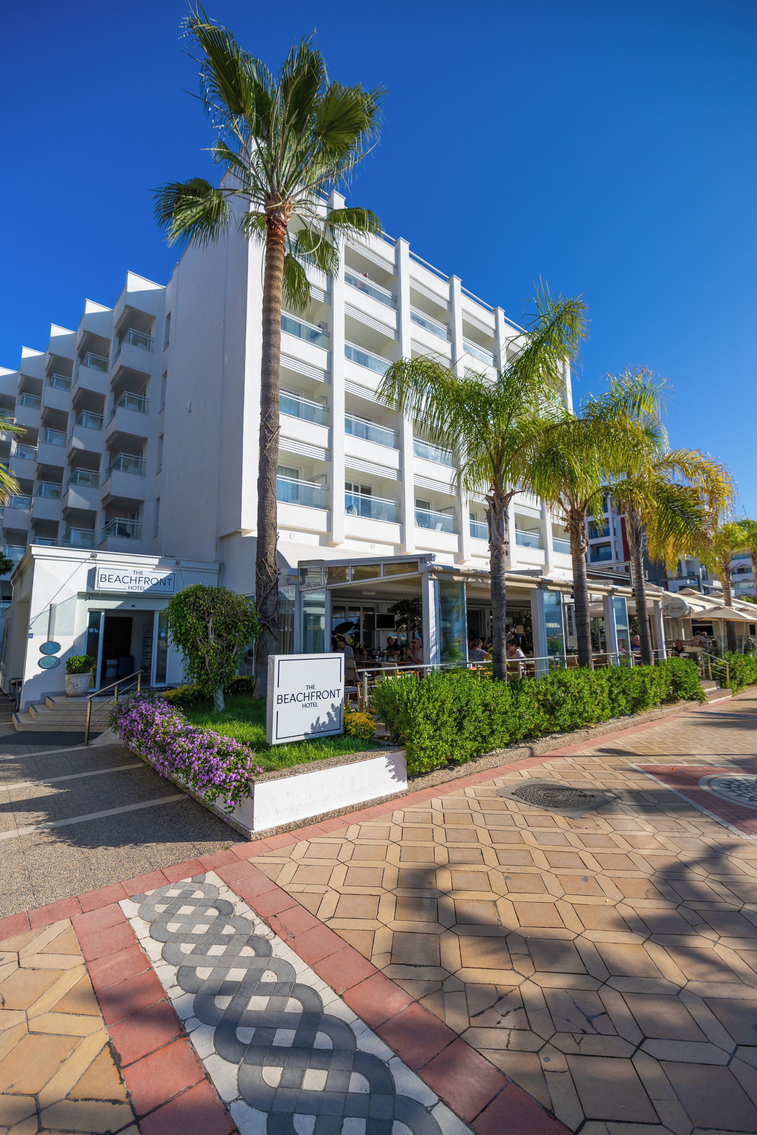 Et hotel med flere etager og et skilt, der viser 'The Beachfront Hotel'.
