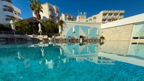 A clear swimming pool with lounge chairs and umbrellas, surrounded by buildings with balconies and a clear sky. - The Beachfront Hotel Adult Only 16 Plus (Marmaris)