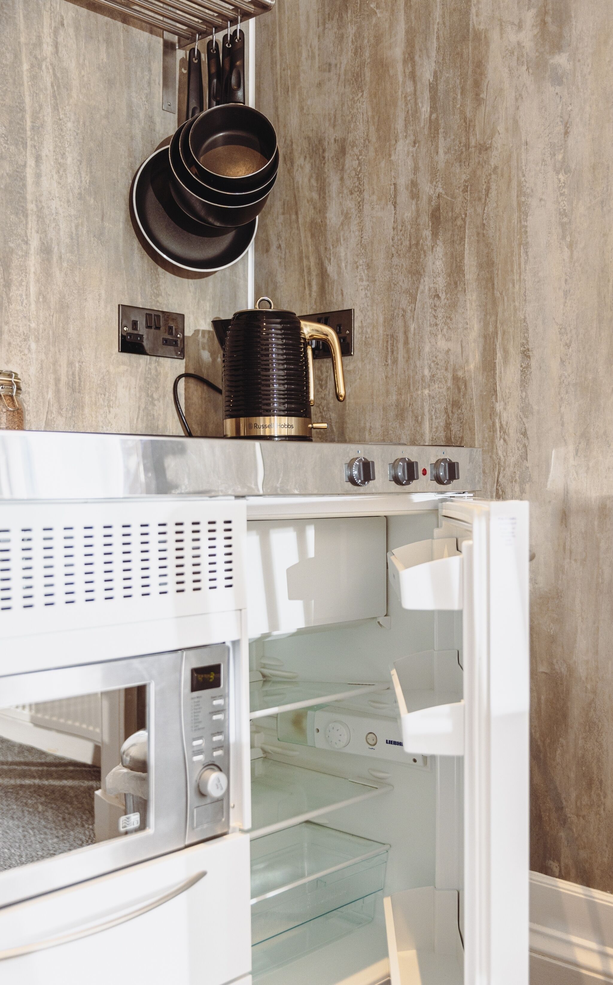 A kitchen with a built-in microwave, a kettle, and a stove.