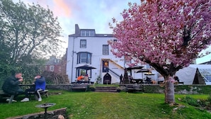 A courtyard with a white building, a cherry blossom tree, and outdoor seating areas. - The Tower Gastro Pub & Apartments (Crieff)