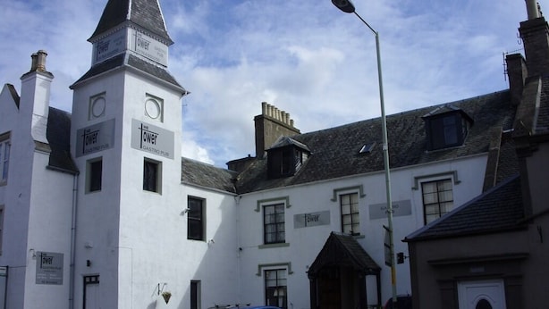 A building with a prominent tower, a sign for 'The Tower Gastro Pub', and a car parked in front. - The Tower Gastro Pub & Apartments (Crieff)
