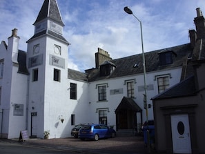 A building with a prominent tower, a sign for 'The Tower Gastro Pub', and a car parked in front. - The Tower Gastro Pub & Apartments (Crieff)