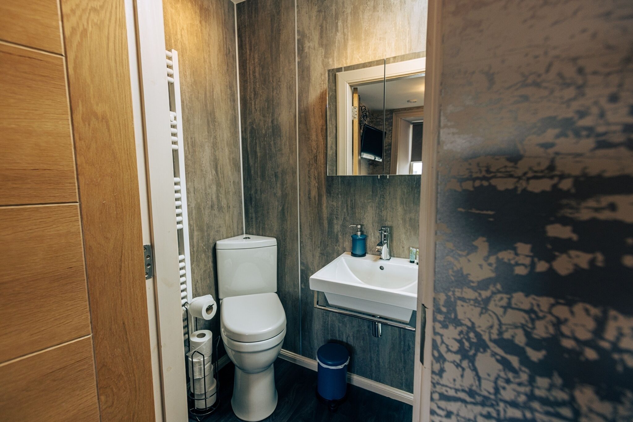 A compact bathroom with a toilet, sink, and mirror.