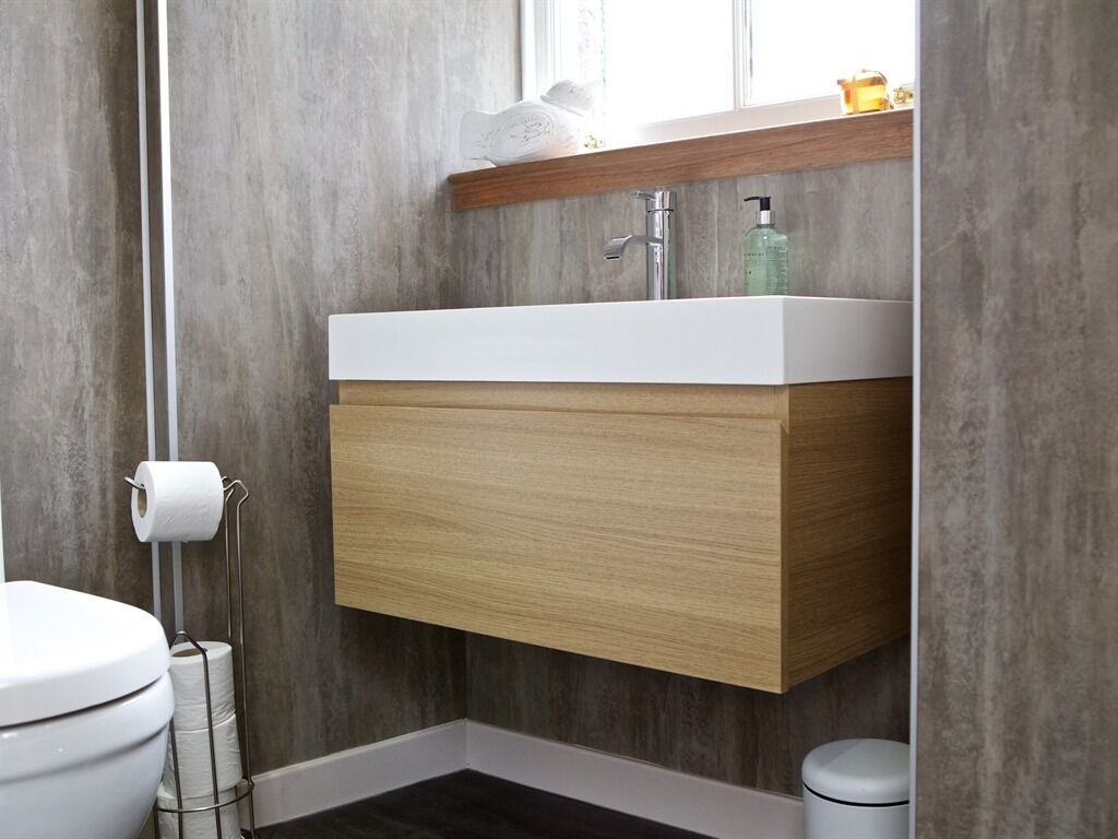 A bathroom with a white sink, wooden vanity, and a toilet.