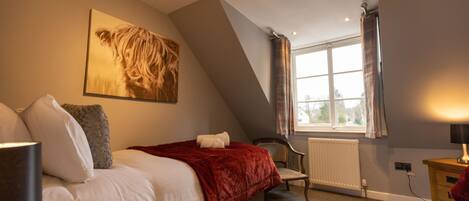 A bedroom with a bed, a chair, a window, and a radiator.