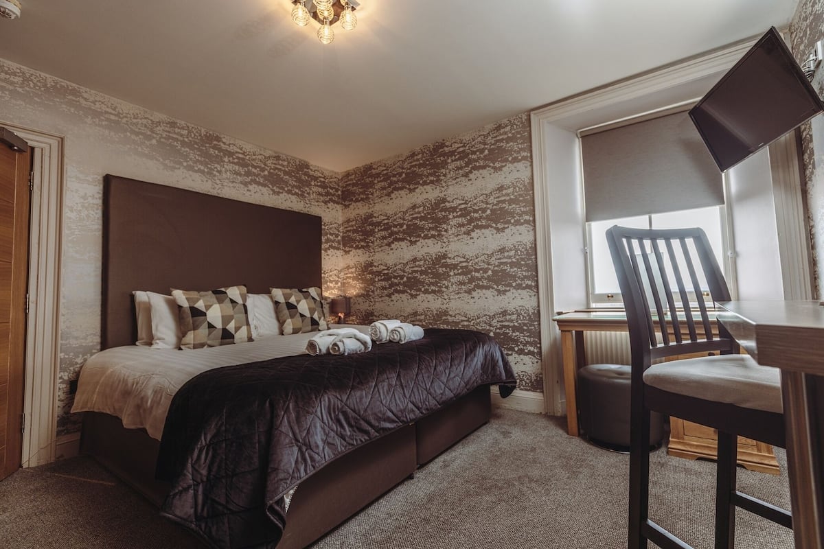 A bedroom with a large bed, a desk, and a chair.