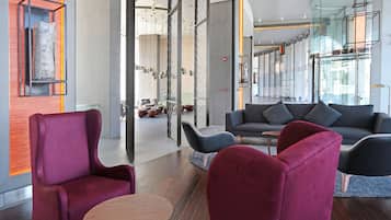 Un interior moderno con una zona de estar que incluye un sofá, sillones, una mesa de madera y un elemento decorativo en la pared.