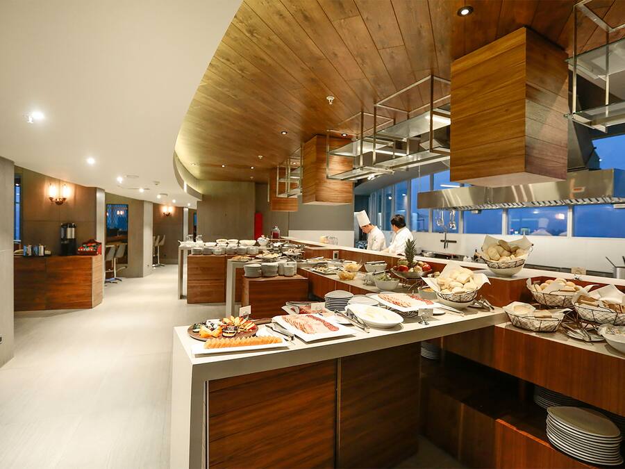 A modern kitchen with wooden accents, a buffet setup, and a visible kitchen area.