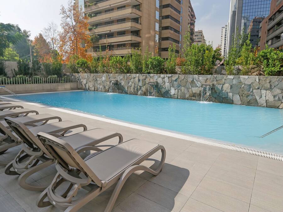 Una piscina con sillones de descanso y un muro de piedra.