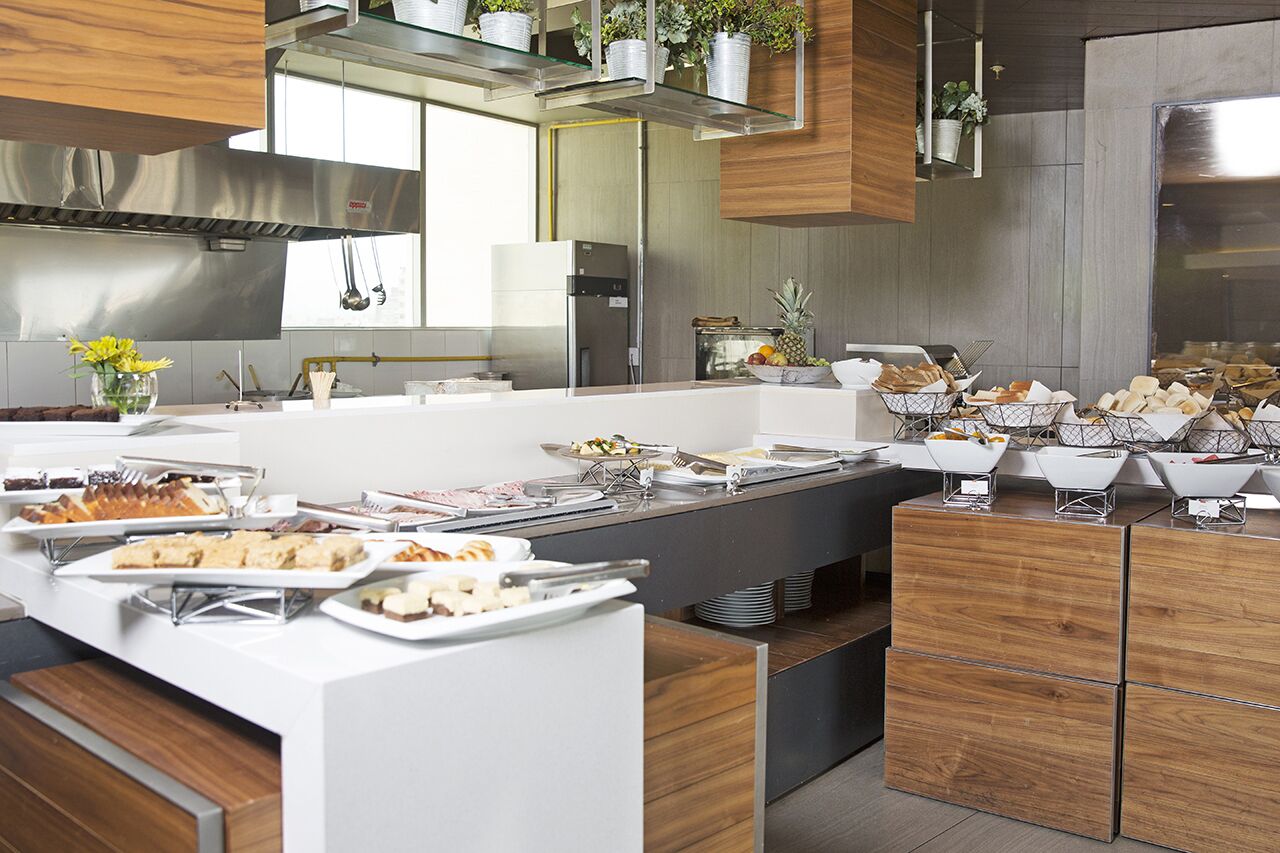 A modern kitchen with a buffet setup, stainless steel appliances, and wooden cabinetry.