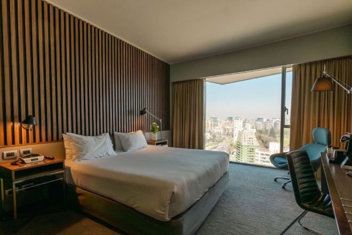Una habitación de hotel moderna con una cama grande, un escritorio y vistas a la ciudad.