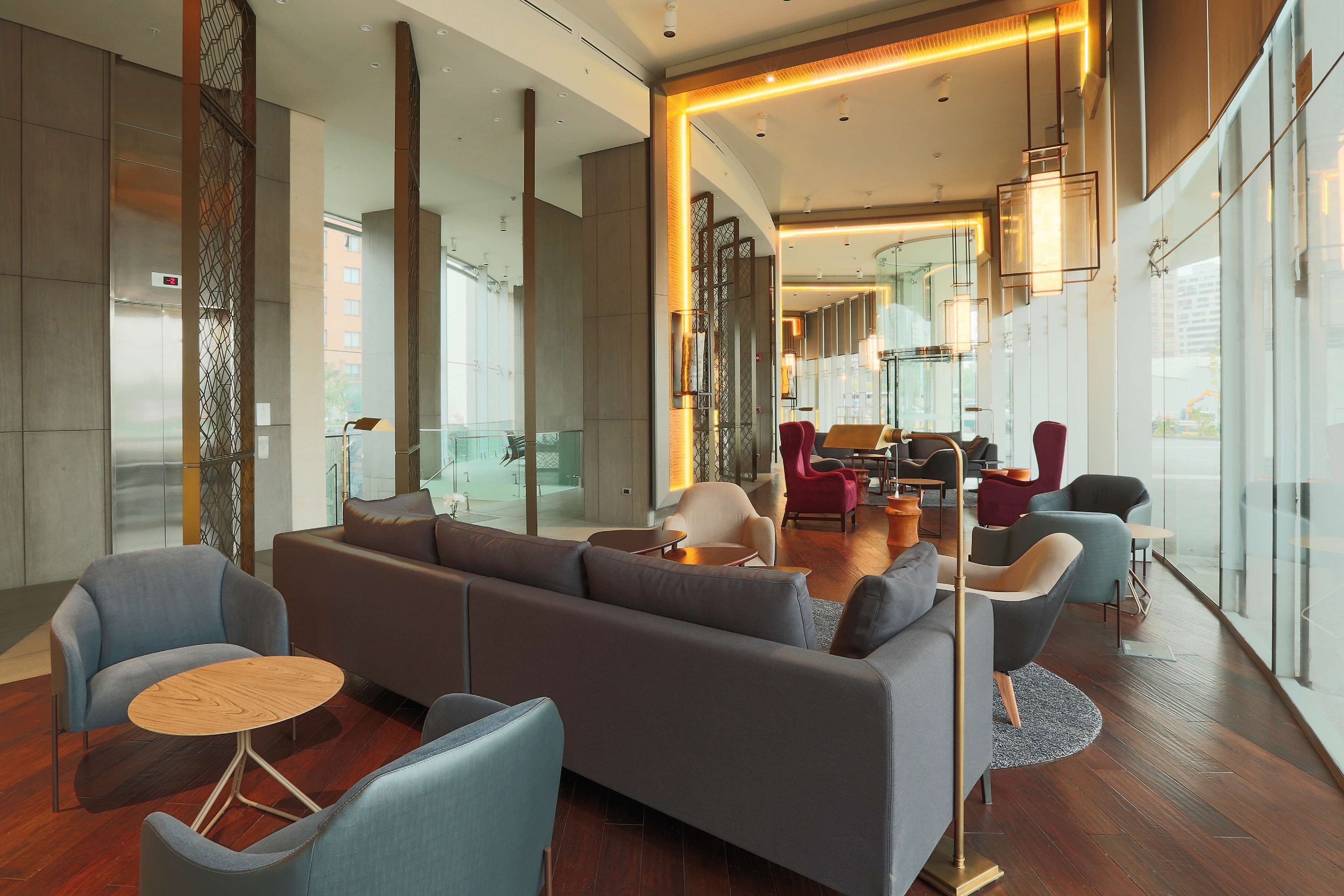 A modern hotel lobby with a sectional sofa, round tables, and comfortable chairs.