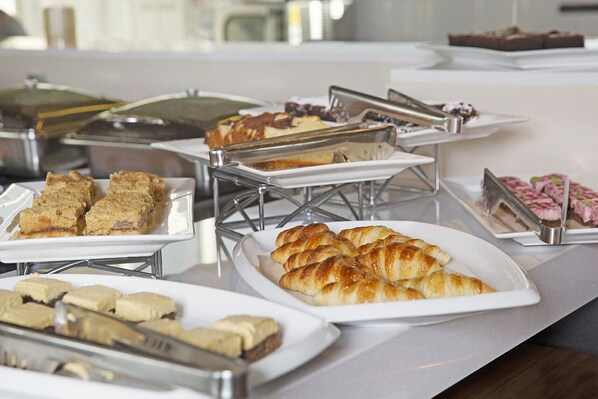 A buffet with various food items including pastries and desserts. - DoubleTree by Hilton Santiago Kennedy (Santiago)