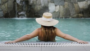 Una persona en una piscina con un muro de piedra al fondo.