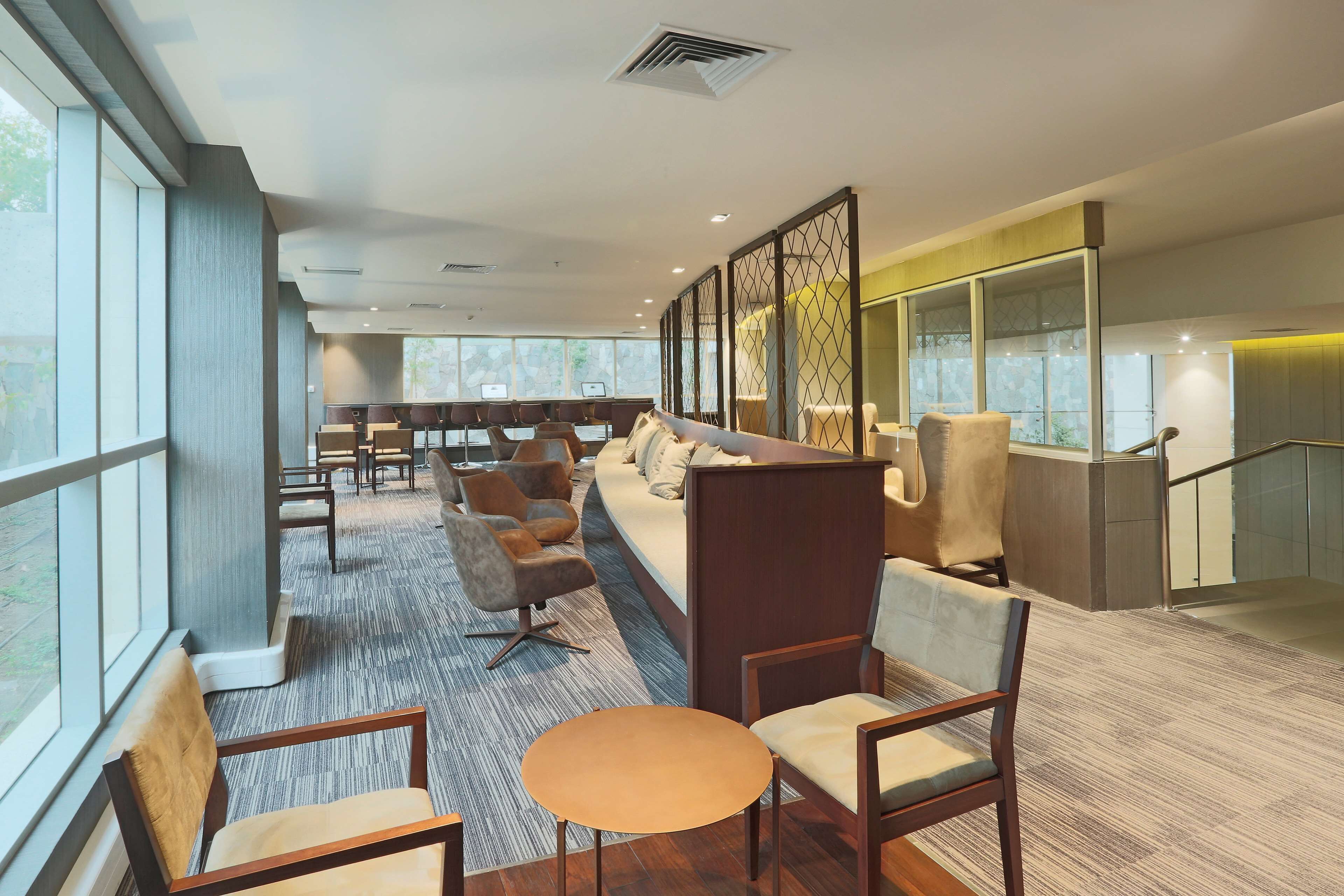 Een moderne hotellobby met zithoeken, grote ramen en een trap.
