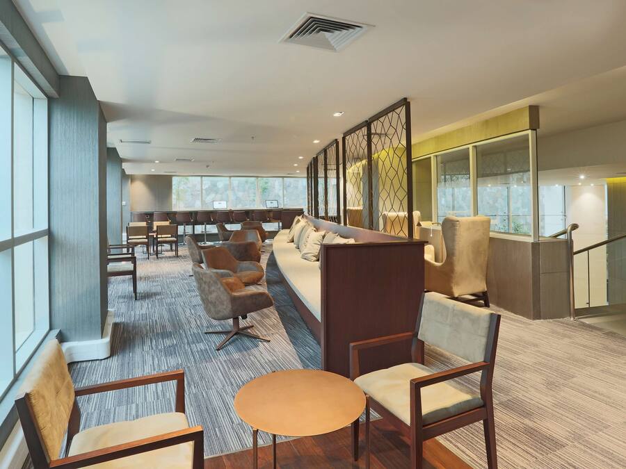A modern hotel lobby with seating areas, large windows, and a staircase.