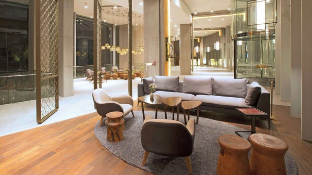 Una sala moderna con sofá, sillas, una mesa de centro y un tapete.