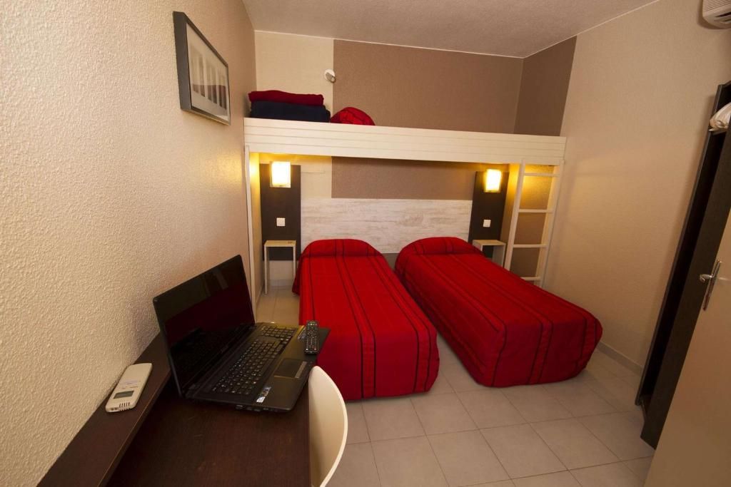 Habitación pequeña con literas, un escritorio con una computadora portátil y una silla.