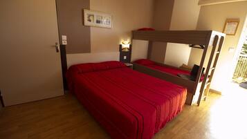 A bunk bed with red bedding, a bedside table with a lamp, and a framed picture on the wall.