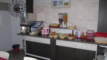 A breakfast bar with various food items, a coffee machine, and a decorative mirror.