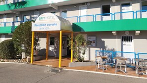 A hotel reception area with a sign indicating it's open from 7 am to 9 pm. - Brit Hotel Essentiel Sète Balaruc (Balaruc-le-Vieux)