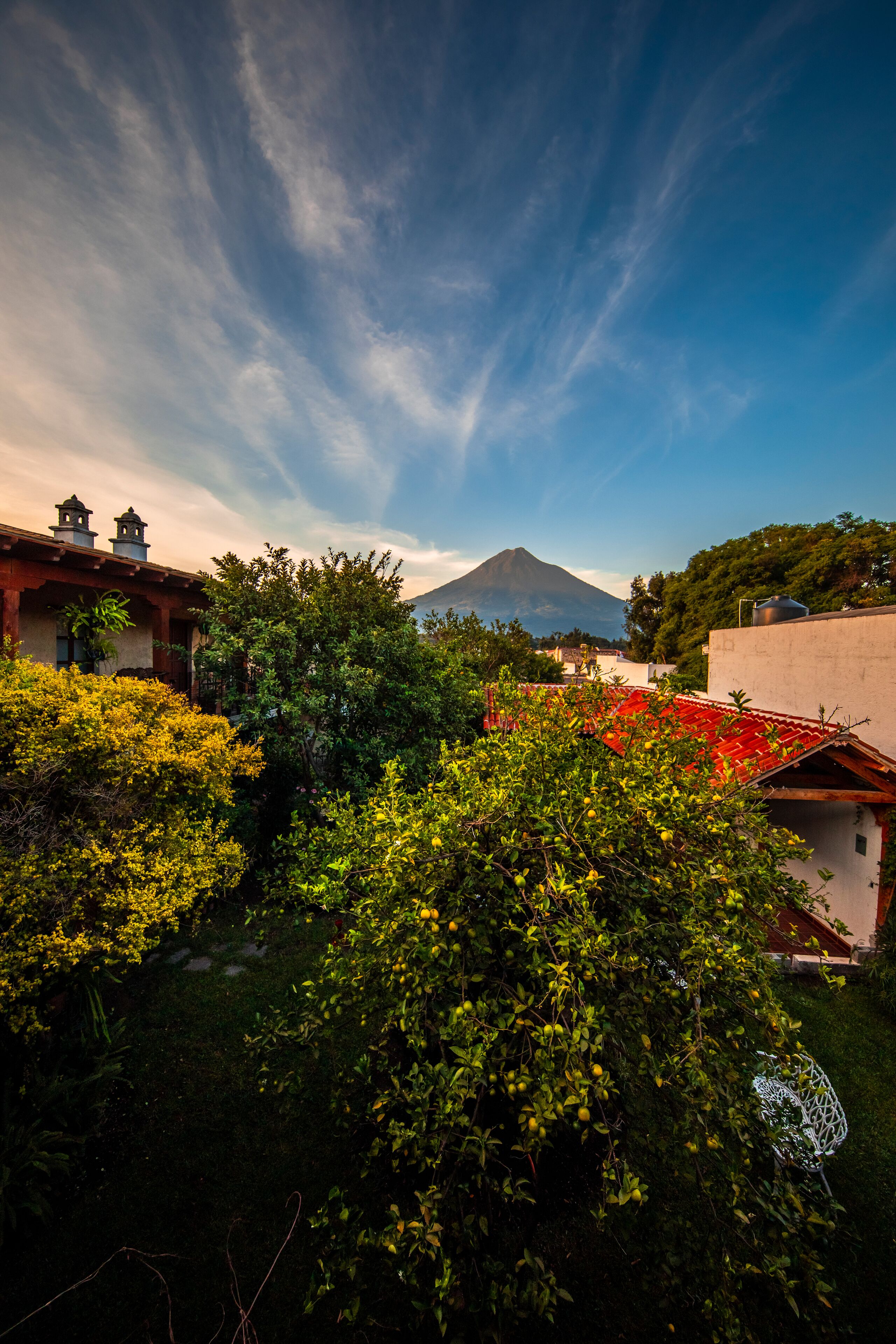 A residential area with a mountain in the background, lush greenery, and traditional architecture.