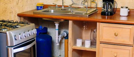 A compact kitchen with a gas stove, stainless steel sink, and a coffee maker.