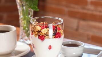 A dessert glass with granola and berries on a white tray.