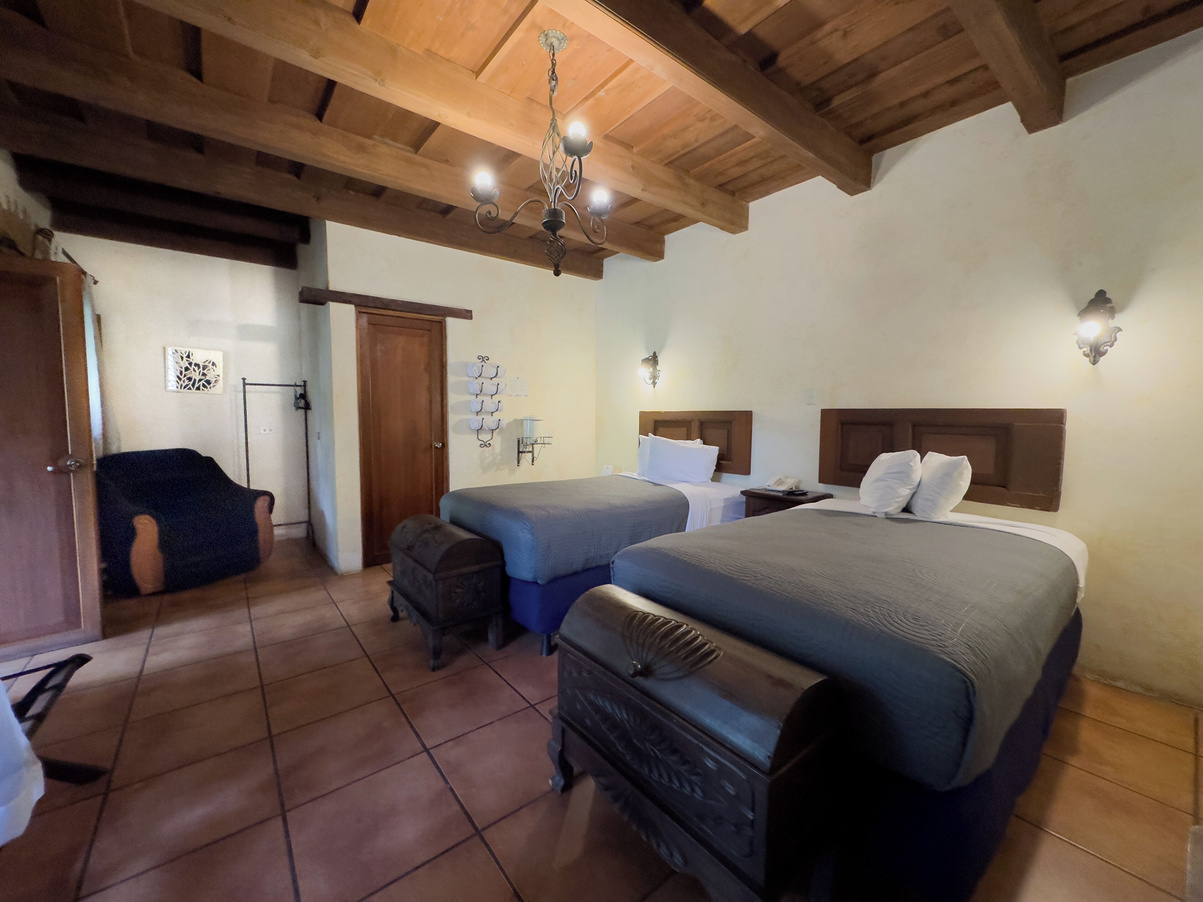 Une chambre avec deux lits, un plafond en bois et un lustre.