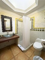 Un baño con tocador, lavamanos, inodoro y ducha con cortina.
